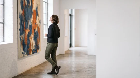 Une personne observe pensivement une œuvre dans une galerie d'art contemporain parisienne baignée de lumière naturelle